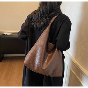 Detail of a large brown hobo tote bag with vintage crinkled leather texture on model