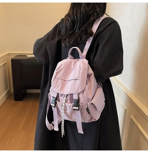 Back view of light purple nylon backpack on model wearing black coat for casual daily use