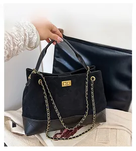 Detail of black quilted suede tote bag featuring a gold clasp and chain strap