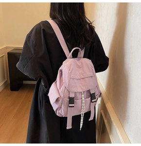 Detail view of lavender nylon backpack featuring black buckles and white drawstring closure