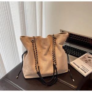 Détail d'un sac cabas en daim beige avec bandoulière chaîne et fermeture à cordon