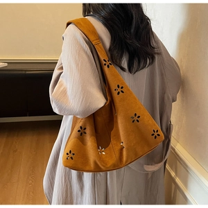 Detail of caramel suede hobo bag featuring laser-cut floral patterns and wide strap