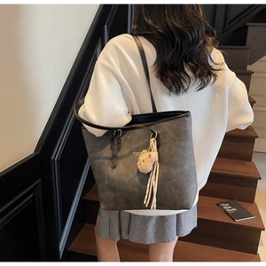 Detail of grey matte tote bag with teddy bear charm and silk scarf on a model