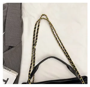 Detail of woven black leather and gold chain shoulder strap on a sleek tote bag