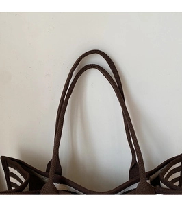 Détail du sac cabas en toile rayée montrant les poignées marron et la doublure intérieure