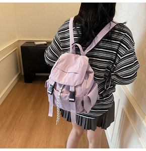 Rear view of a minimalist light purple nylon backpack with flap and black buckle detail