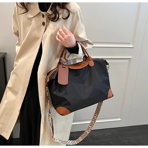 Detail of black nylon tote bag with leather trim and geometric patterned shoulder strap