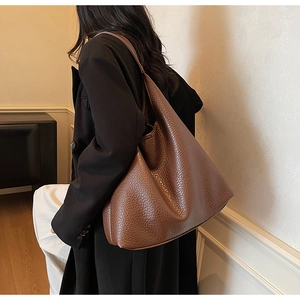 Detail of deep brown pebbled leather hobo bag worn by model in a minimal room