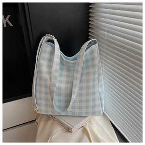Dettaglio della borsa tote a quadretti celeste con logo dorato e ciondolo a catena