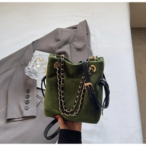 Détail du sac seau en daim vert foncé avec bandoulière chaîne dorée et cordon de serrage