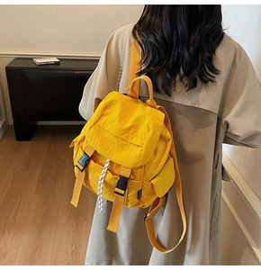 Detail of bright yellow nylon backpack with buckle closure and woven drawstring on model
