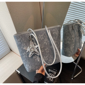 Detail of grey-blue tote bag with floral print, silver tubular handle and star charm