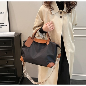 Detail of nylon tote bag with leather handles and wave pattern shoulder strap worn by model