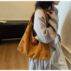 Brown suede tote bag with flower cutout design shown on shoulder for daily commute
