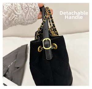Detail of black suede bucket bag with quilted patterns and golden hardware accents