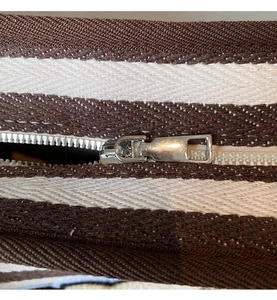 Gros plan du détail de la fermeture éclair en métal sur un sac cabas en toile rayée