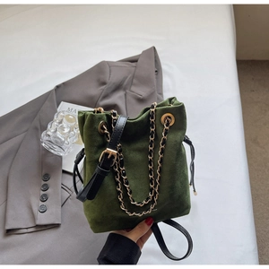 Détail du sac seau en daim vert foncé avec bandoulière noire et chaîne dorée chic