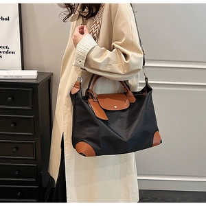 Detail of nylon tote bag with leather handles and patterned strap worn by a model