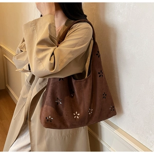 Close-up of coffee brown suede tote bag with laser-cut floral hollow patterns on the side
