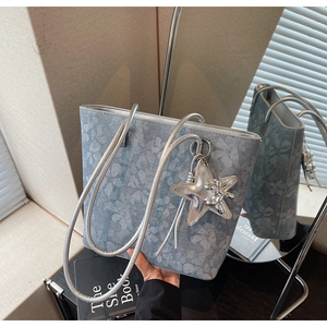 Close-up of blue-grey printed tote bag with silver star charm and floral pattern