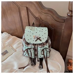Detail of checkered student backpack with green star patterns and brown ribbon bows