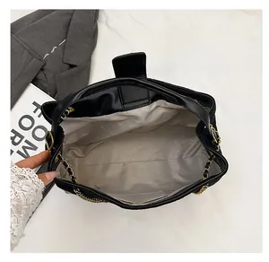 Internal view of black suede tote bag with large capacity and gold chain strap detail