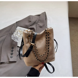 Détail du sac seau beige mat avec chaîne dorée et fermeture par cordon