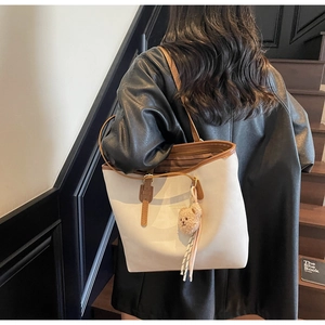 Rear view of a model wearing the cream and brown tote bag with bear charm detail