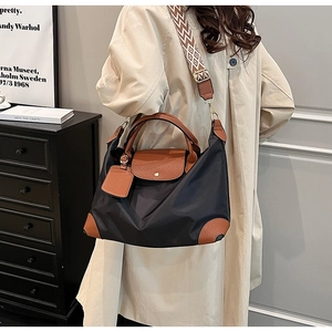 Detail of navy nylon tote bag with leather handles and patterned crossbody strap