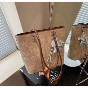 Close-up of printed tote bag with leather strap and silver starfish charm accessory