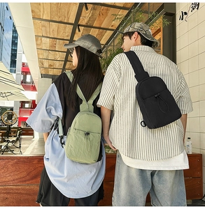 Detail of light green and black nylon sling bags with adjustable straps in urban setting