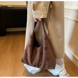 Detail view of brown suede tote bag featuring intricate floral laser-cut patterns