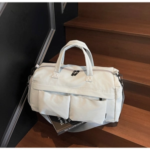 Detail of light grey travel bag with front pockets on a wooden stairs background