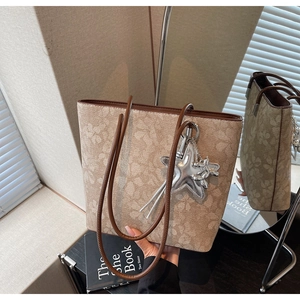 Detail of floral tote bag with brown leather straps and silver star pendant accessory
