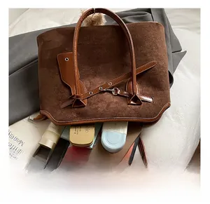 Detail showing high-capacity interior of brown suede tote bag with books and cosmetics