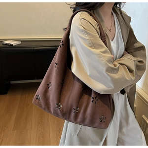 Detail of dark brown suede tote bag with floral laser cut-out pattern on a model