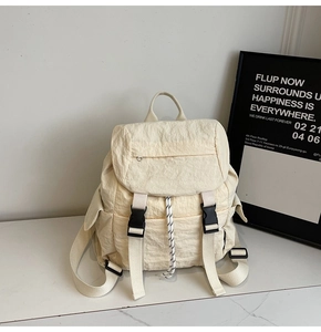 Detail view of off-white nylon backpack with drawstring closure and black buckle straps