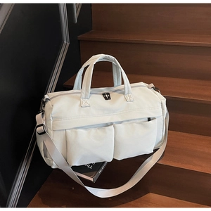 Detail view of large travel bag with front pockets and adjustable strap on stairs