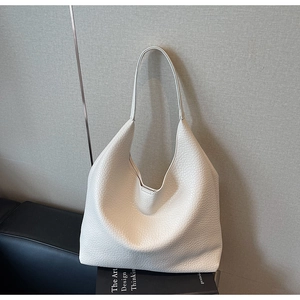 Detail shot of the cream-colored hobo bag showing its premium lychee grain texture