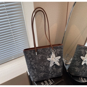 Close-up of printed tote bag with brown leather straps and silver star pendant detail