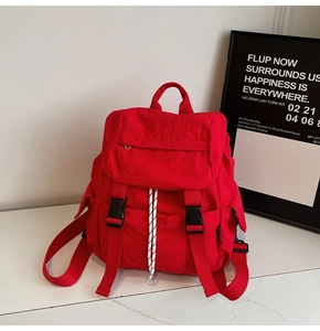 Detail view of red nylon backpack with black buckle closure and woven drawstring features