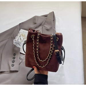 Détail d'un sac seau en daim marron avec chaîne dorée et fermeture à cordon