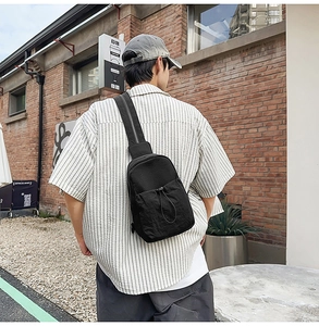 Outdoor street style shot of a black durable nylon crossbody chest bag with drawstring pocket