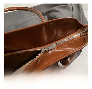 Detail of silver metal zipper on dark brown leather tote with cream lining