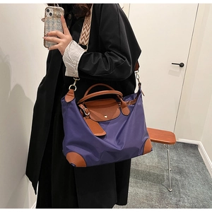 Detail view of purple nylon tote with brown leather handles and wavy pattern strap