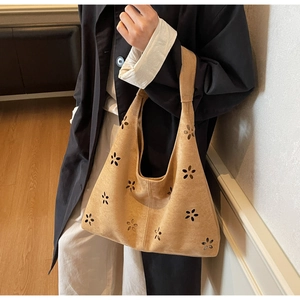 Detail of khaki suede tote bag featuring intricate floral laser-cut hollow patterns