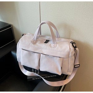 Detail view of water-resistant nylon travel bag with dual zip pockets on a leather bench