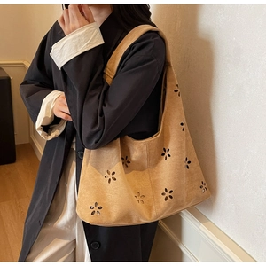 Detail of laser-cut floral pattern on caramel suede tote bag shown on a shoulder