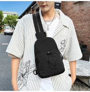 Close-up of black nylon chest bag featuring drawstring pocket and adjustable strap