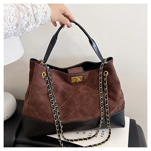 Detail of vintage quilted tote bag featuring brown suede stitching and a metal turn-lock